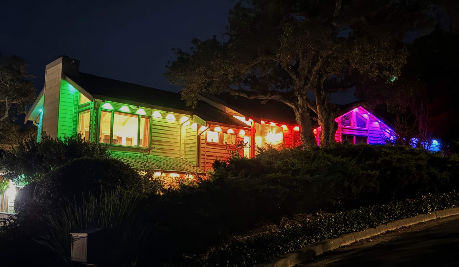 Large estate home with smart permanent roofline LED lighting at night showing color gradient