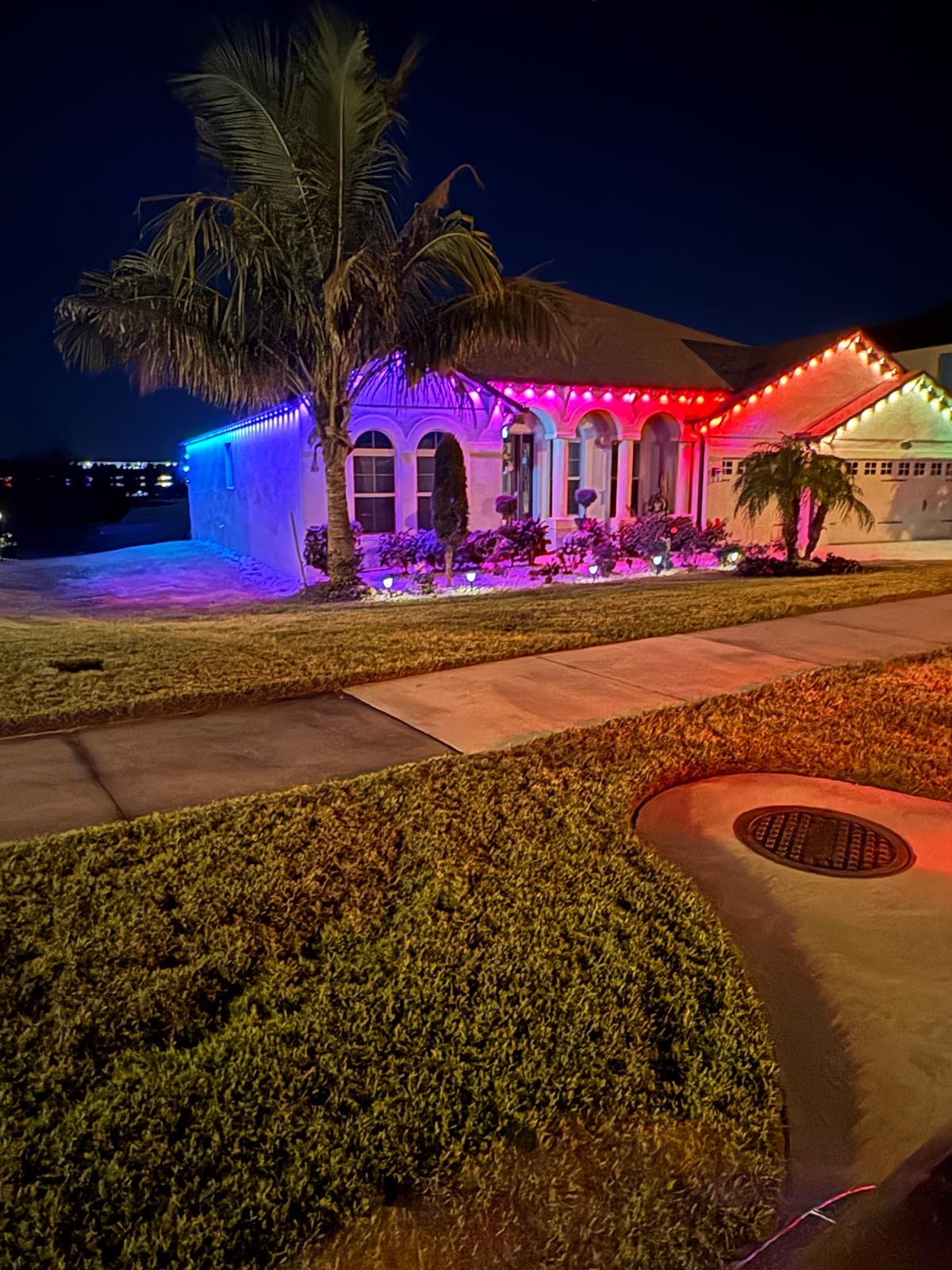 Single-story waterfront home with colorful rainbow gradient roofline lighting