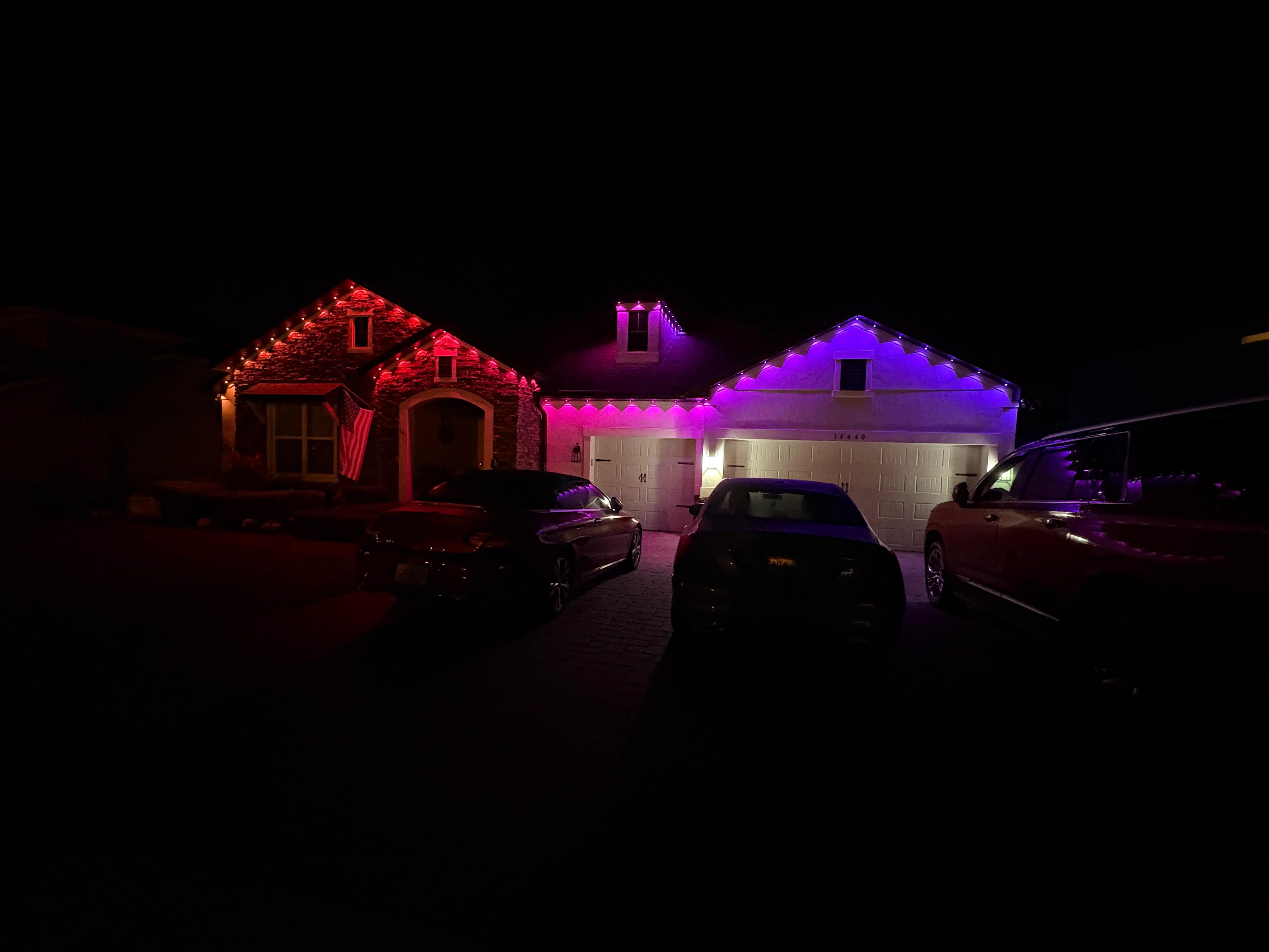 Multi-color permanent LED lighting with red, pink and purple on house roofline